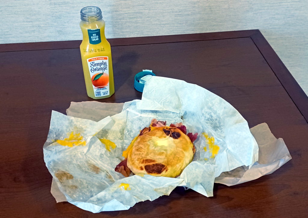 a sandwich on a paper and a bottle of juice