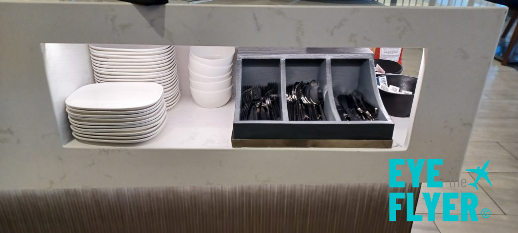 a shelf with a container of utensils and plates