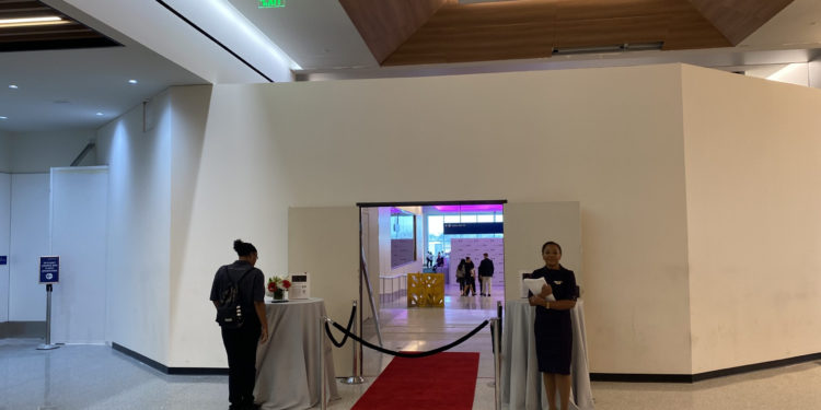 a woman standing in a room with a red carpet and a rope barrier