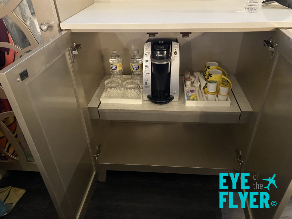 a coffee machine and cups under a cabinet