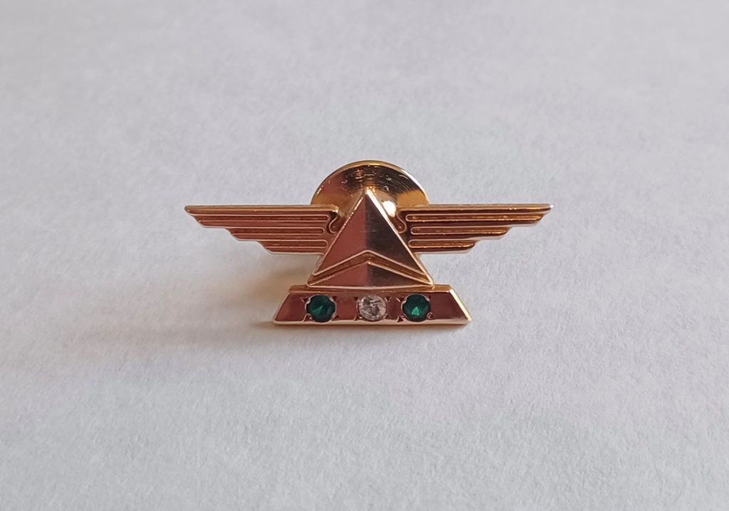 a gold pin with wings and gemstones
