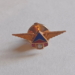 a gold pin with wings and a blue triangle