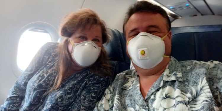 a man and woman wearing masks on an airplane