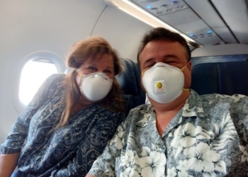 a man and woman wearing masks on an airplane
