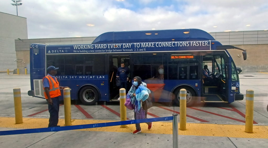 a blue bus with people walking out of it