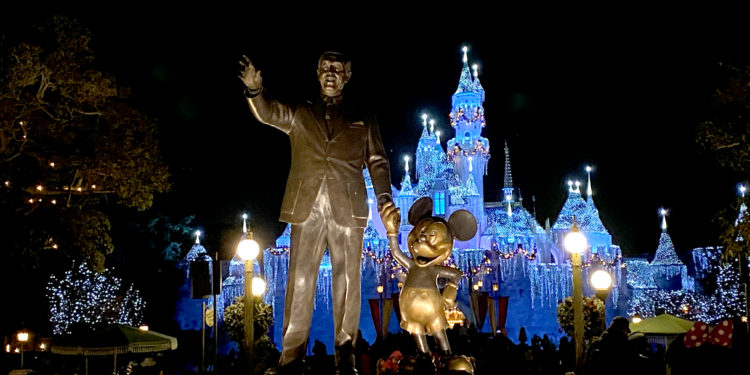a statue of a man and mouse in front of a castle