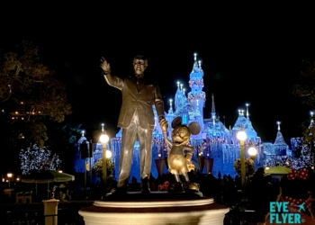 a statue of a man and mouse in front of a castle