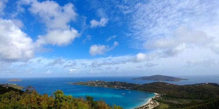 a body of water with land and trees and blue sky