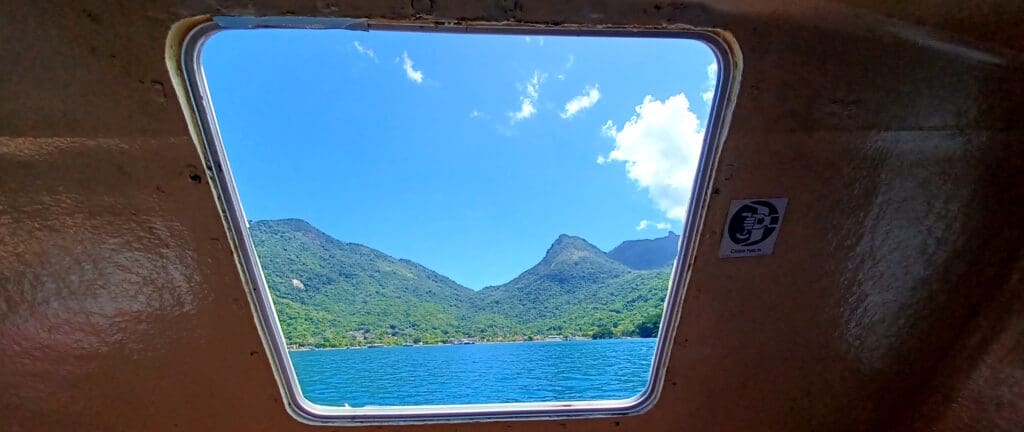 a window with a body of water and mountains in the background