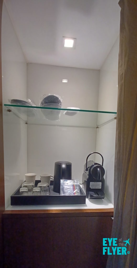 a glass shelf with a coffee pot and cups on it