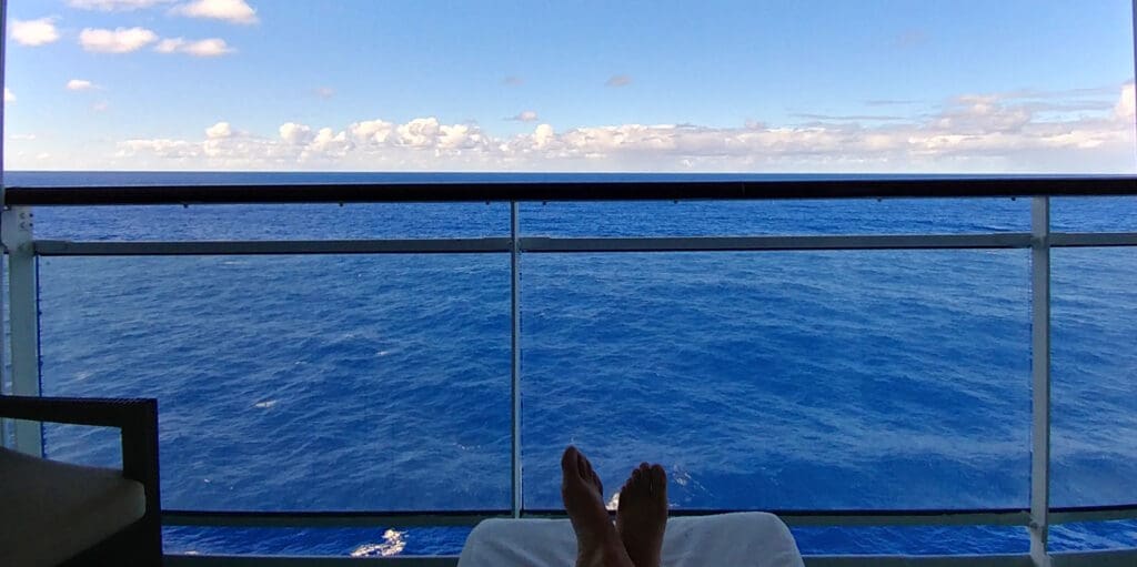 a person's feet on a deck overlooking the ocean