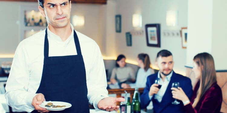Portrait of waiter dissatisfied with small tip from cafe visitors (©iStock.com/JackF)