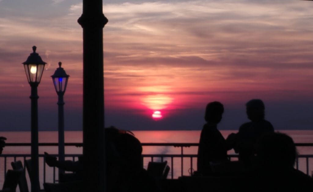 a group of people sitting at a table with a lamp and a sunset