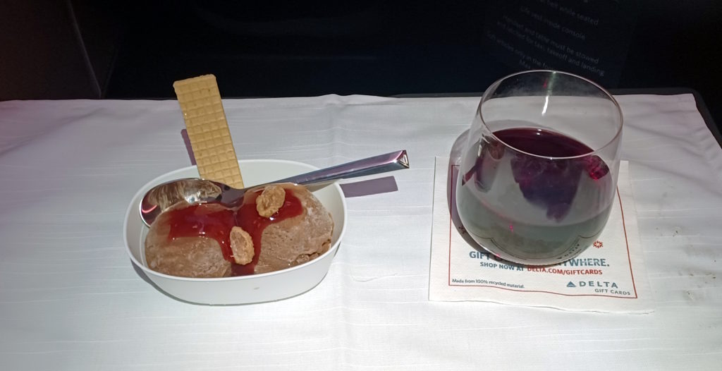 a bowl of ice cream with a spoon and a glass of wine
