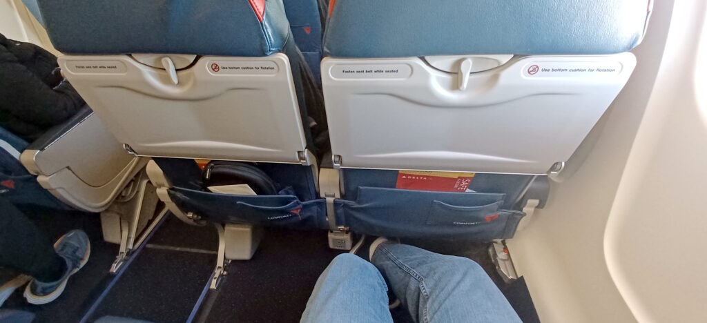 a person's legs and a seat in an airplane