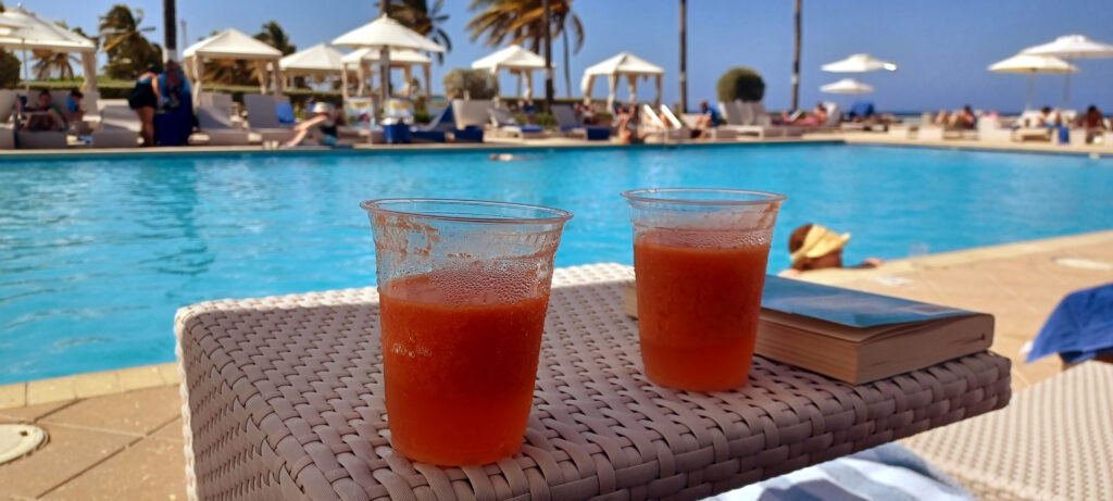 two cups of orange liquid next to a pool