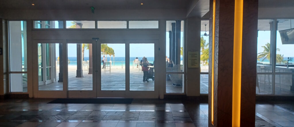 a glass doors with people walking on the beach