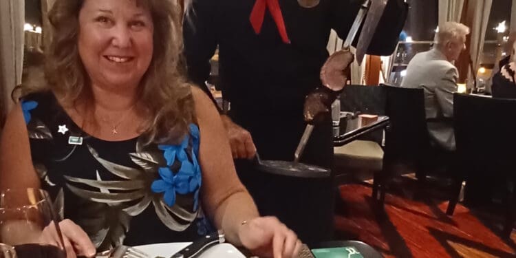 a man holding a knife and a woman sitting at a table with food