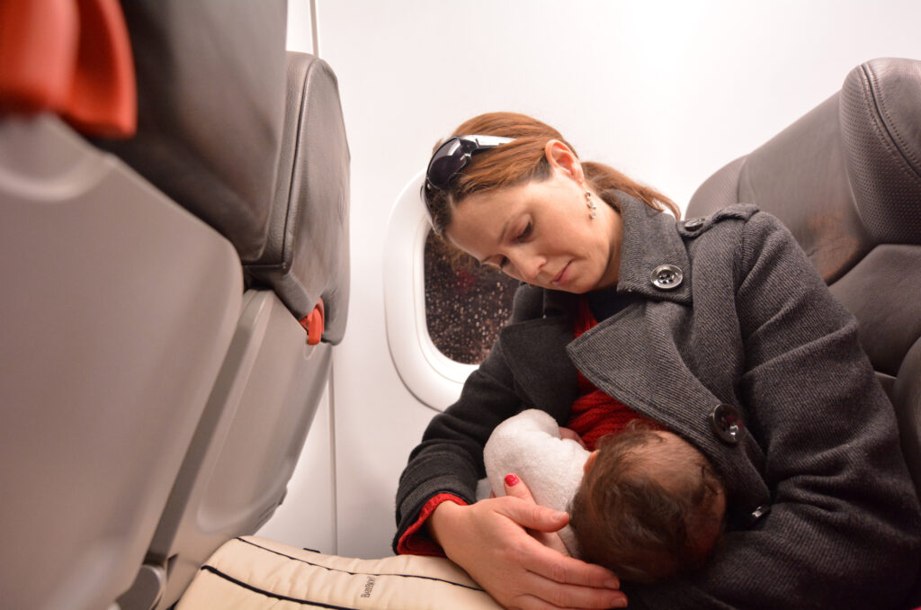 Mother breastfeeding her newborn baby during flight. Concept photo of air travel with baby.
