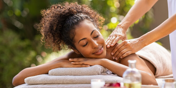 a woman lying on a towel with hands on her shoulder