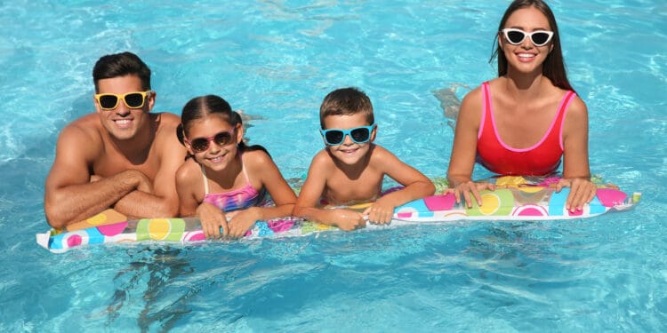 Happy family on inflatable mattress in hotel swimming pool