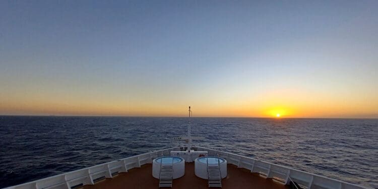 a deck of a ship with a hot tub and a sunset