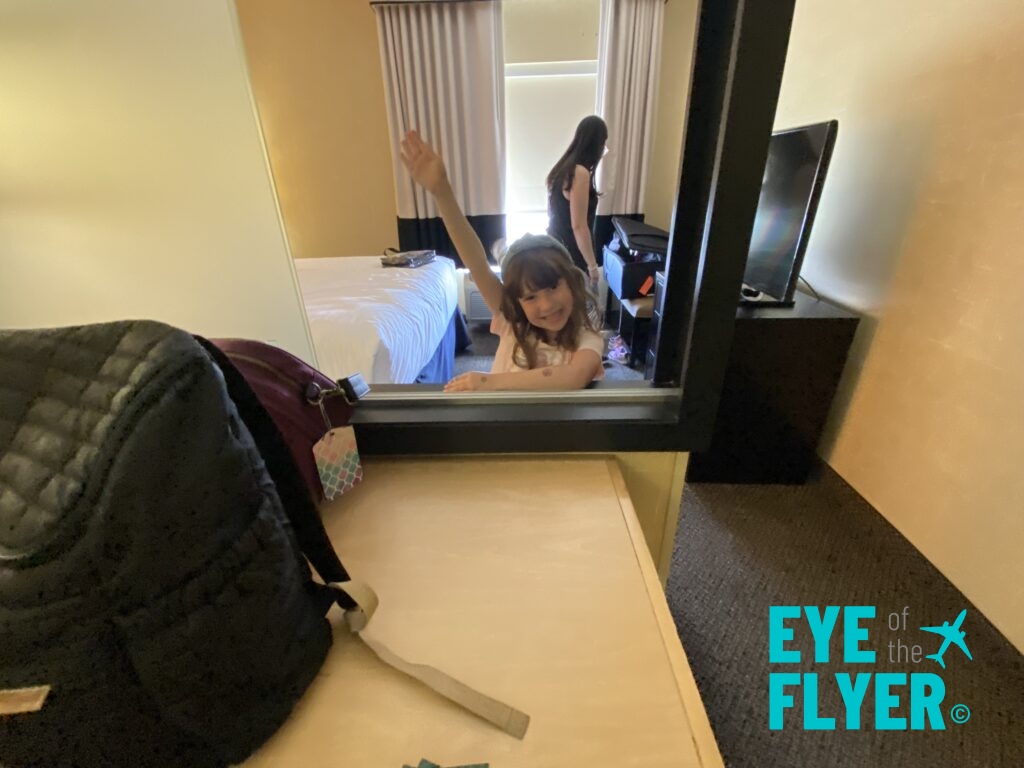 a girl in a room with a backpack and a mirror
