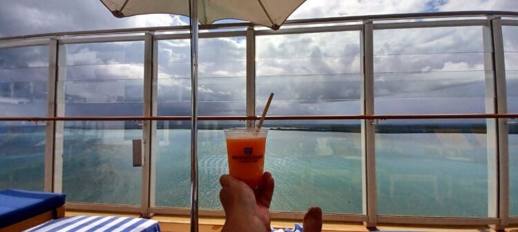 a person holding a drink in front of a body of water
