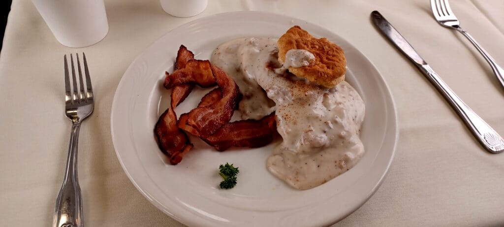 a plate of food with a biscuit and bacon