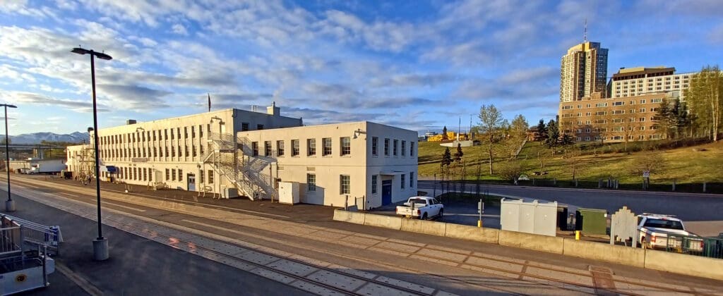 a white building with stairs and a car parked in front of it