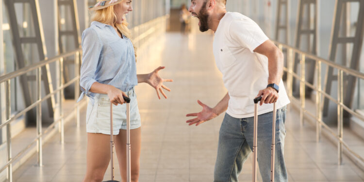 Couple arguing at airport terminal, forgot some things at home, side view