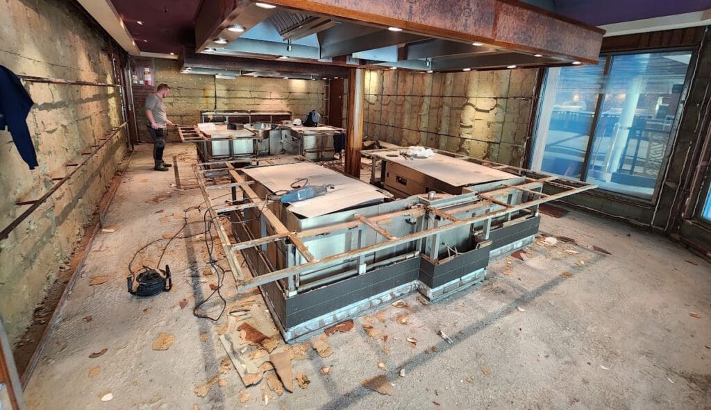 a group of men standing in a room with metal tables