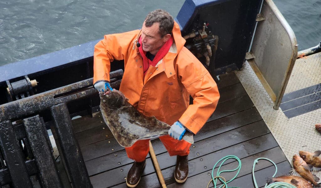 a man in an orange raincoat holding a large fish