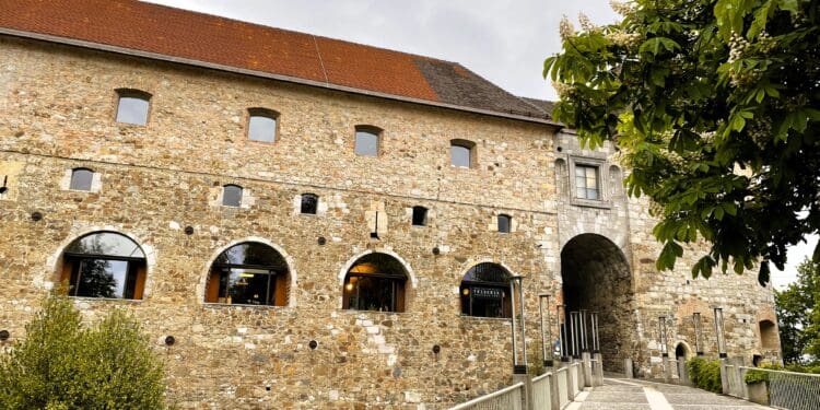 a stone building with a walkway and trees