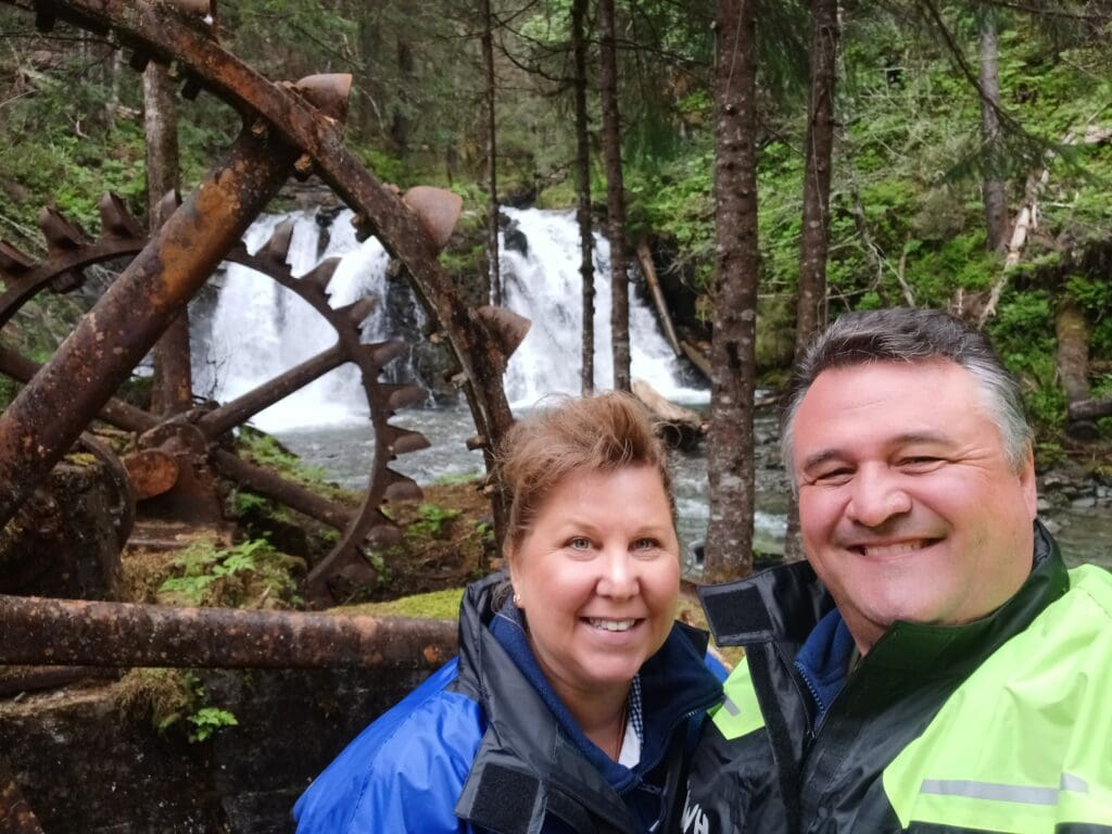 a man and woman standing in front of a water fall