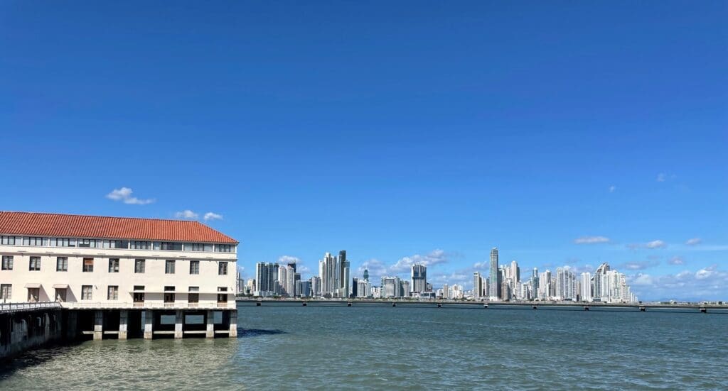 a building on a dock in the water with a city in the background