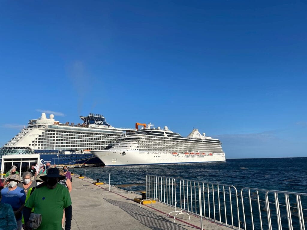 a group of cruise ships in the water with RMS Queen Mary in the background