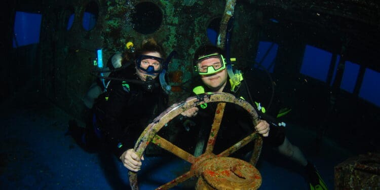 two people in scuba gear holding a steering wheel