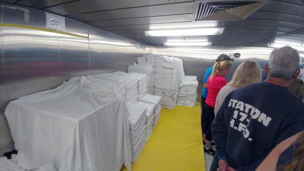 a group of people standing in a room with stacks of white sheets