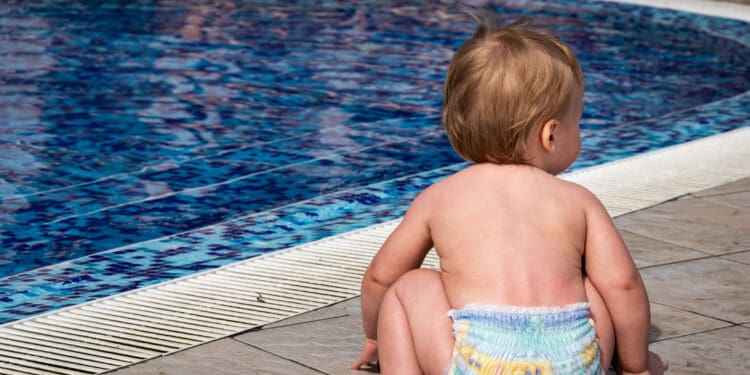 A closeup shot of a cute baby boy playing next to the swimming pool