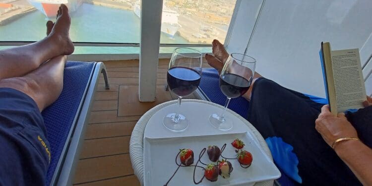 a person's feet on a deck with wine glasses and strawberries
