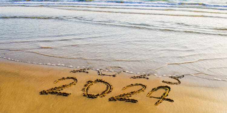 happy new year 2024 text on the sea beach. Abstract conceptual photo of coming New Year 2024 and leaving year of 2023, a clean handwritten new year greetings on a shoreline (©iStock.com/prospective56)