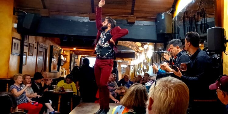 a man in a red suit standing on a stage with his arms raised
