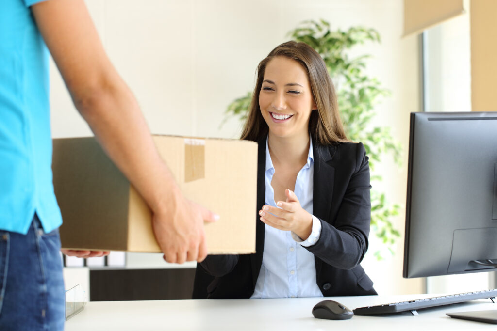 Happy businesswoman receiving a package sitting on a desk at office