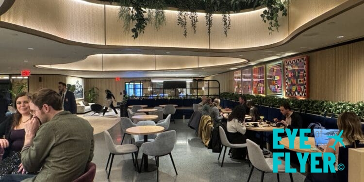 a group of people sitting at tables in a room with art and plants