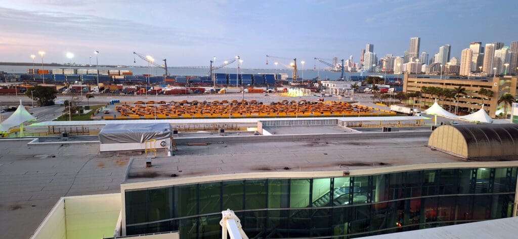 a large parking lot with many cars and cranes in the background