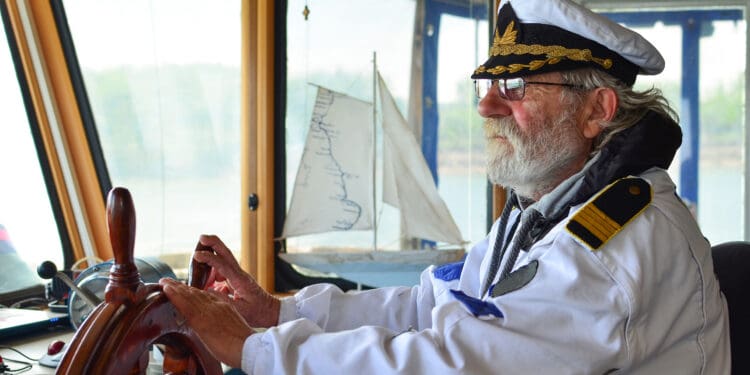 Ship navigation, experienced captain, old sea dog with grey hair and beard on his working place, ship navigation cabin