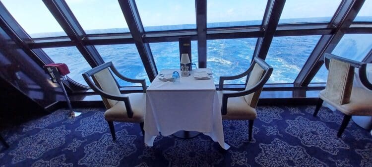 a table with chairs and a white tablecloth in a room with a large window