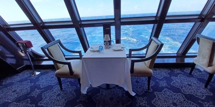 a table with chairs and a white tablecloth in a room with a large window