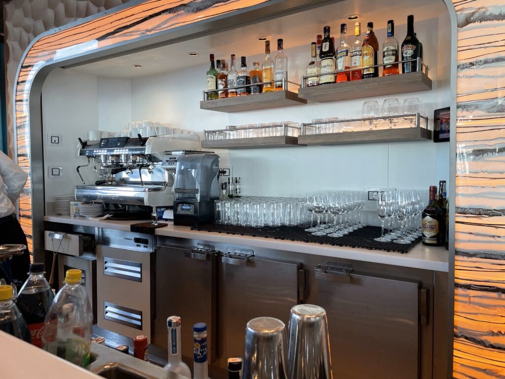 a bar with many glasses and bottles on shelves